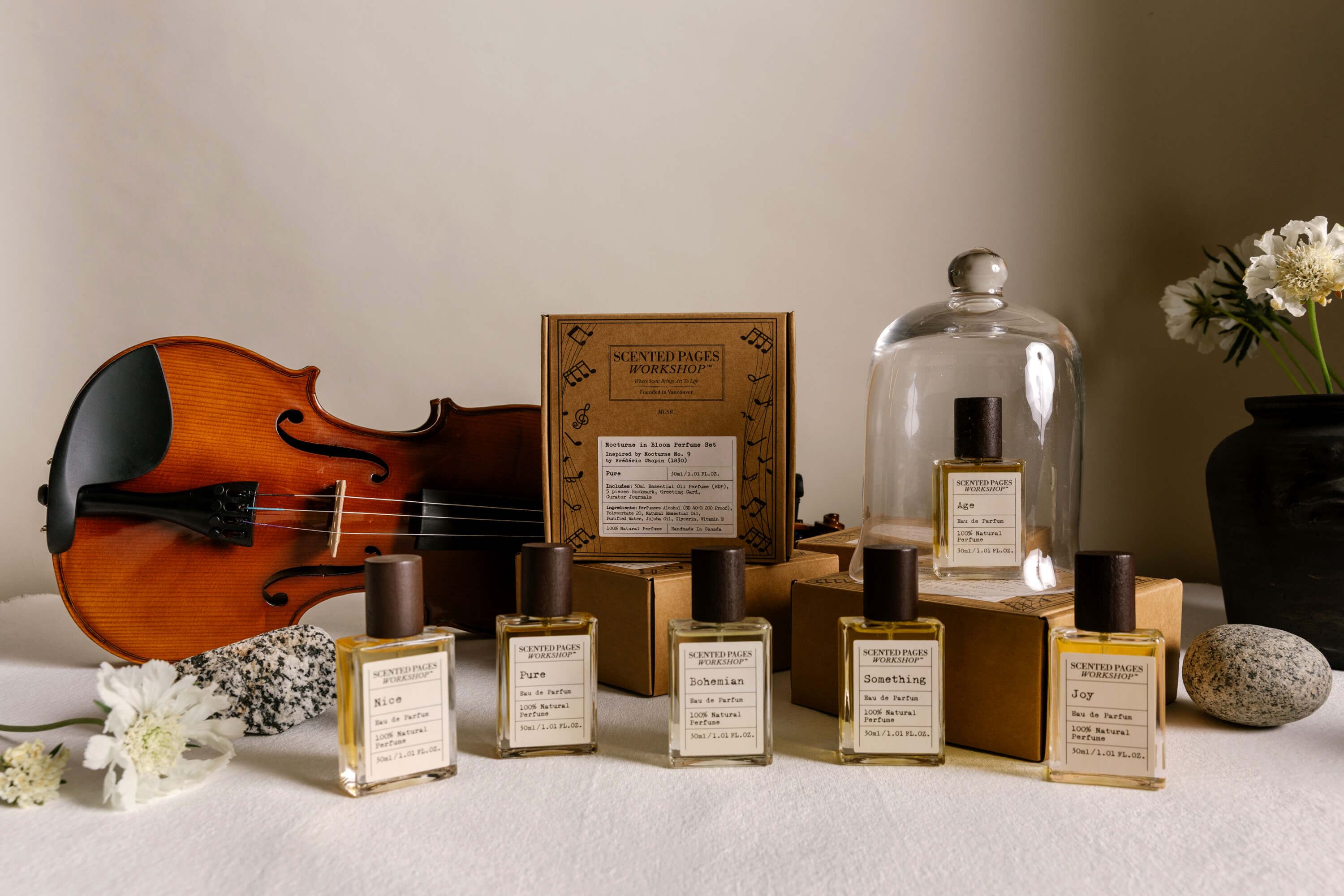Perfume collection by Scented Pages Workshop inspired by music, with eau de parfum bottles arranged beside a violin.
